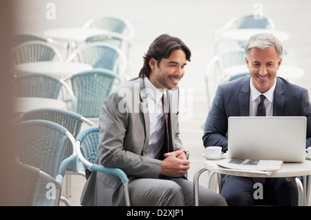 Smiling businessman using laptop at sidewalk cafe Stock Photo