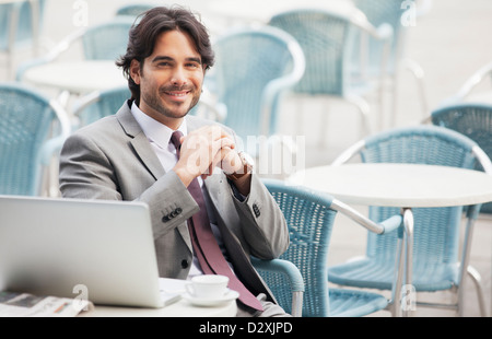 Portrait of smiling businessman with laptop and espresso at sidewalk cafe Stock Photo