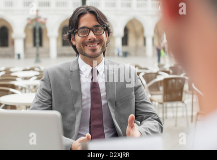 Smiling businessman talking to co-worker at sidewalk cafe Stock Photo