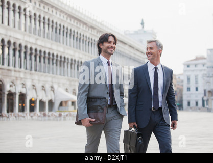 Smiling businessmen walking across St. Mark's Square in Venice Stock Photo