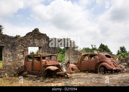 Two burnt out cars  that are very rusty in a destroyed building, the cars have no wheels. Stock Photo