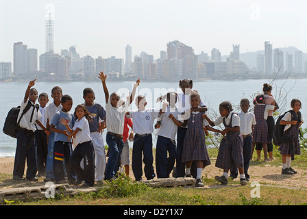 Colombia, Tierrabomba, portrait of schoolgirls and schoolboys standing together with arm around, cityscape in the background Stock Photo