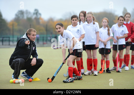 A games teacher instructs girls during hockey practice at Pates Grammar School in Cheltenham, Gloucestershire UK Stock Photo