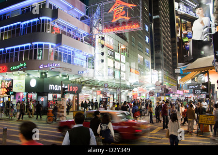 People shopping in Hong Kong with neon street signs at night Stock Photo