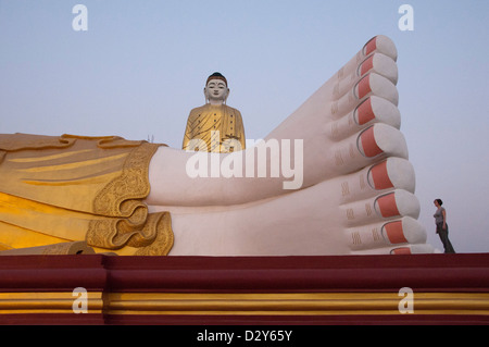 Feet of enormous reclining Buddha with Bodhi Tataung, giant standing buddha behind. Monywa, Myanmar (Burma) Stock Photo