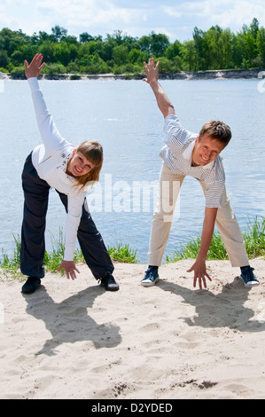 Woman and personal trainer are doing exercises near river Stock Photo