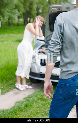 Male back with worried young woman near her broken car Stock Photo