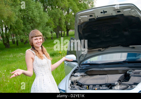 Worried young woman near her broken car with non-urban background Stock Photo