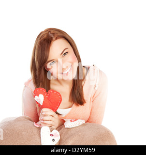 Picture of cute young lady with red handmade heart-shaped soft toy isolated on white background, Valentine day, romantic gift Stock Photo