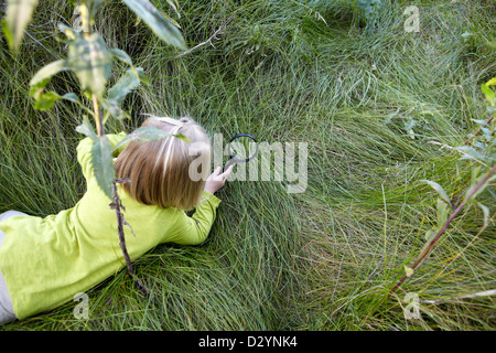 Toddler in field looking through magnifying glass Stock Photo