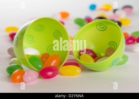 Decorated plastic Easter egg open with colorful jelly beans out of focus in background. Isolated on white background Stock Photo