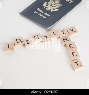 Identity theft spelled in Scrabble letters with US passport out of focus in the background. Isolated on white background. Stock Photo