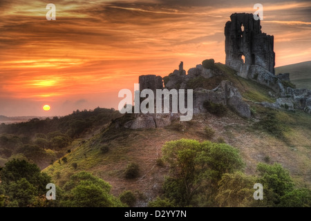 Landscape with castle ruins on hill and vibrant beautiful sunrise in distance Stock Photo