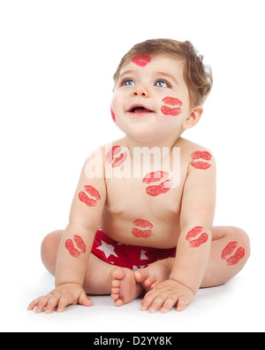 Photo of happy kid covered with red kisses print on the body, adorable baby boy sitting in studio isolated on white background, Stock Photo