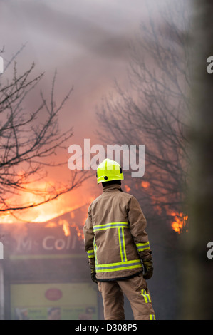 Fireman assess a burning shop building blazing in England, UK Stock Photo