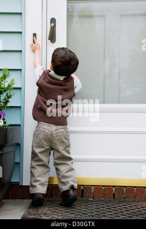 A young boy reaching and ringing a doorbell. Stock Photo