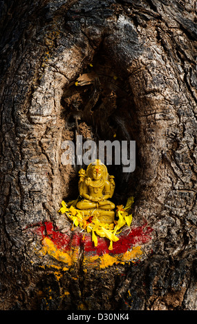 Lord Shiva statue and flower petals in a tree hollow. India Stock Photo