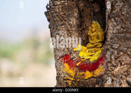 Lord Shiva statue and flower petals in a tree hollow. India Stock Photo