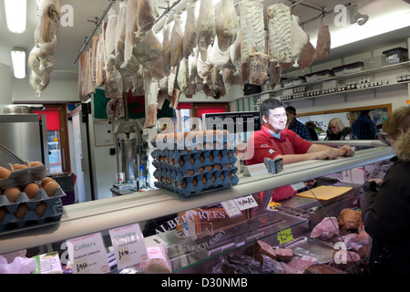 Albert Rees farm butchers selling fresh meat hanging pork in the covered market at Carmarthen, Carmarthenshire, Wales, UK Stock Photo