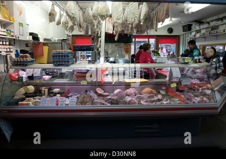 Albert Rees farm butchers selling fresh meat hanging pork in the covered market at Carmarthen, Carmarthenshire, Wales, UK Stock Photo