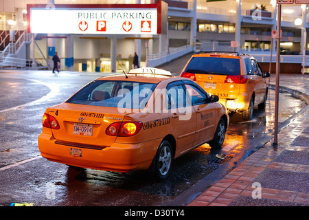 row of yellow cabs outside canada place at night Vancouver BC Canada Stock Photo