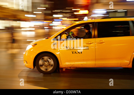 yellow cab taxi downtown Vancouver city at night BC Canada deliberate motion blur Stock Photo