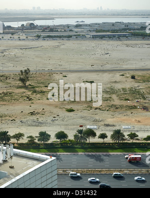 A barren field in Dubai with buzzing traffic nearby Stock Photo