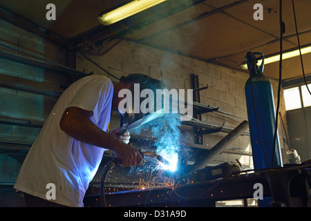 Welder in mask working on steel in factory, Europe Stock Photo