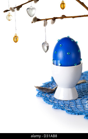 Easter composition with egg and ament on crocheted doily on white background. Egg painted and hand decorated Stock Photo