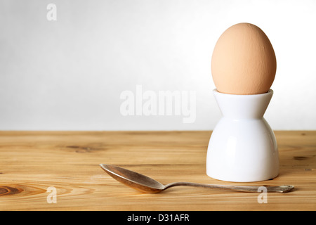 Easter composition with egg on stand and spoon on wooden background. Egg painted a beige paint Stock Photo