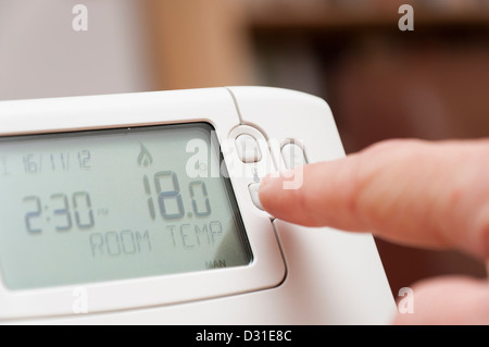 Adjusting room temperature on a home thermostat to save money on heating energy bills. Stock Photo