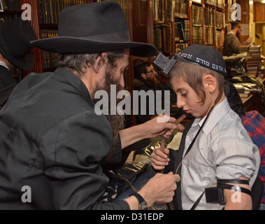 Father instructs his son in how to put on phylacteries (teffilin) in preparation for his Bar Mitzvah Stock Photo