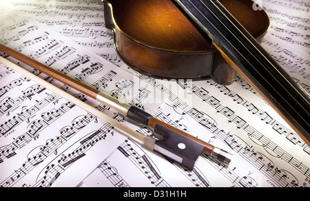 Old wooden violin and bow on scores. Stock Photo