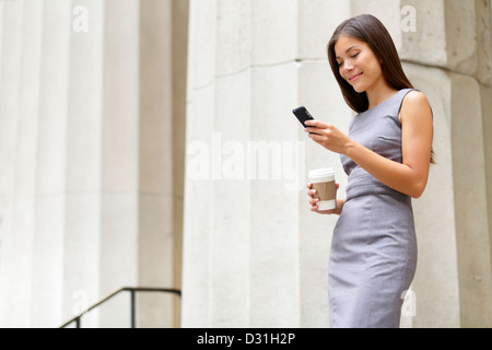Young multiethnic female professional looking at smartphone and drinking coffee in front of courthouse Stock Photo
