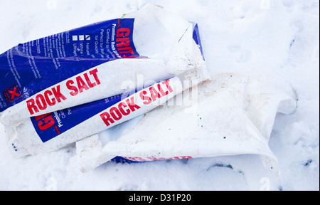 Plastic sacks of Rock Salt and grit on a snowy ground. In preparation for gritting a footpath. Stock Photo