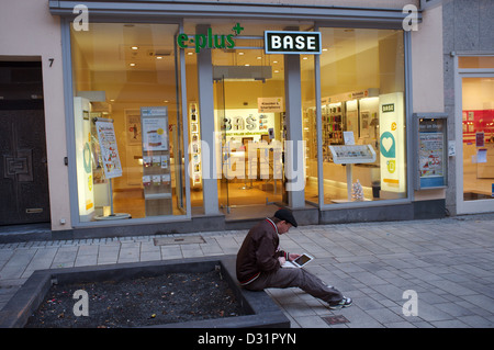 Man using laptop outside a Base mobile phone shop Stock Photo