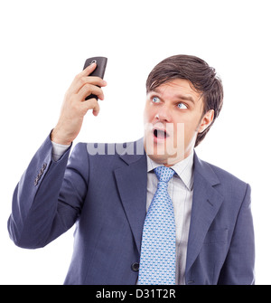 Young businessman holding a mobile phone and looking surprised against white Stock Photo