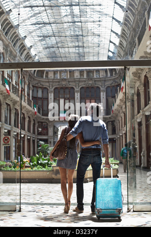 Caucasian couple pulling luggage into ornate building Stock Photo