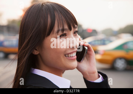 Young businesswoman using the phone outside on the street in Beijing, close up portrait Stock Photo