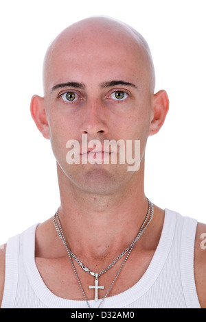 A portrait of a young bald caucasian man with big hazel eyes wearing a white singlet and silver crucifix staring into camera Stock Photo