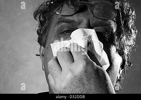 middle-aged man blowing his nose into a tissue, black and white Stock Photo