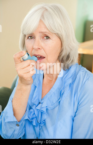 Elderly woman with asthma using inhaler to alleviate symptoms Stock ...