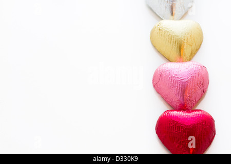 Heart shape chocolate candies wrapped in colorful foil for Valentine's Day. Stock Photo