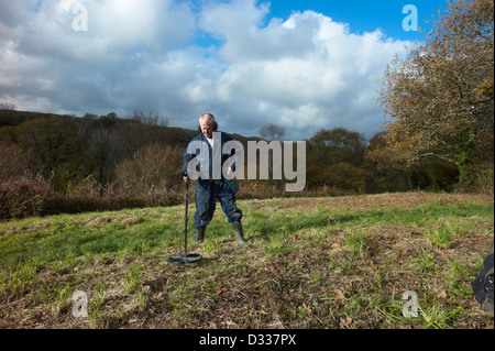 Man using a metal detector in field near Luxulyan Cornwall  Stock Photo