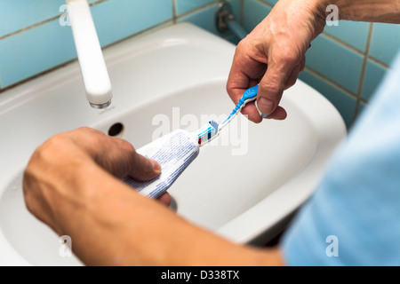 Close up of male hands with toothbrush and toothpaste in bathroom. Stock Photo
