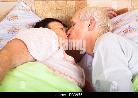 Close up of loving senior couple kissing in bed. Stock Photo