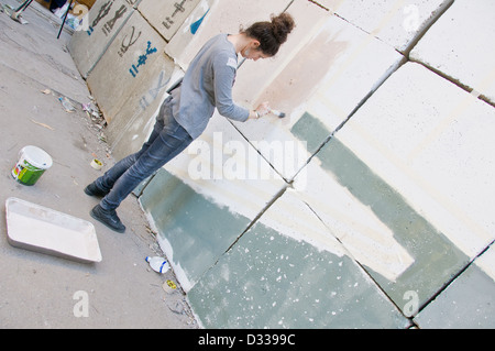 Female artist painting a concrete wall erected by the army in downtown Cairo Egypt Stock Photo