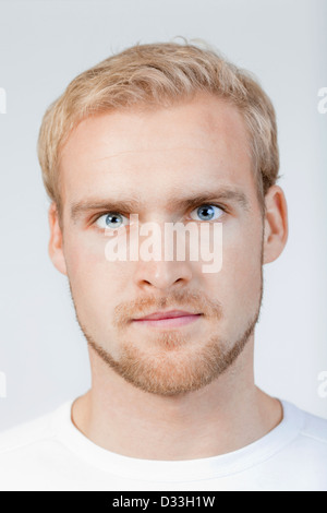 portrait of a young man with blond hair standing- isolated on light gray Stock Photo