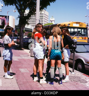 Archival photo of group of teenagers high school girls wearing 1989 1990 fashion standing in the street with a yellow American school bus in Westwood Village Los Angeles LA California USA KATHY DEWITT Stock Photo