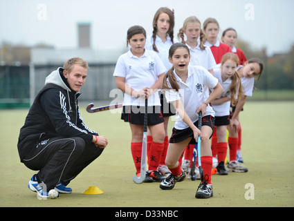 A games teacher instructs girls during hockey practice at Pates Grammar School in Cheltenham, Gloucestershire UK Stock Photo